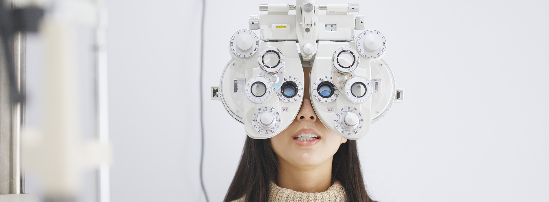 An individual wearing a pair of eye glasses and positioned in front of an ophthalmic examination device.