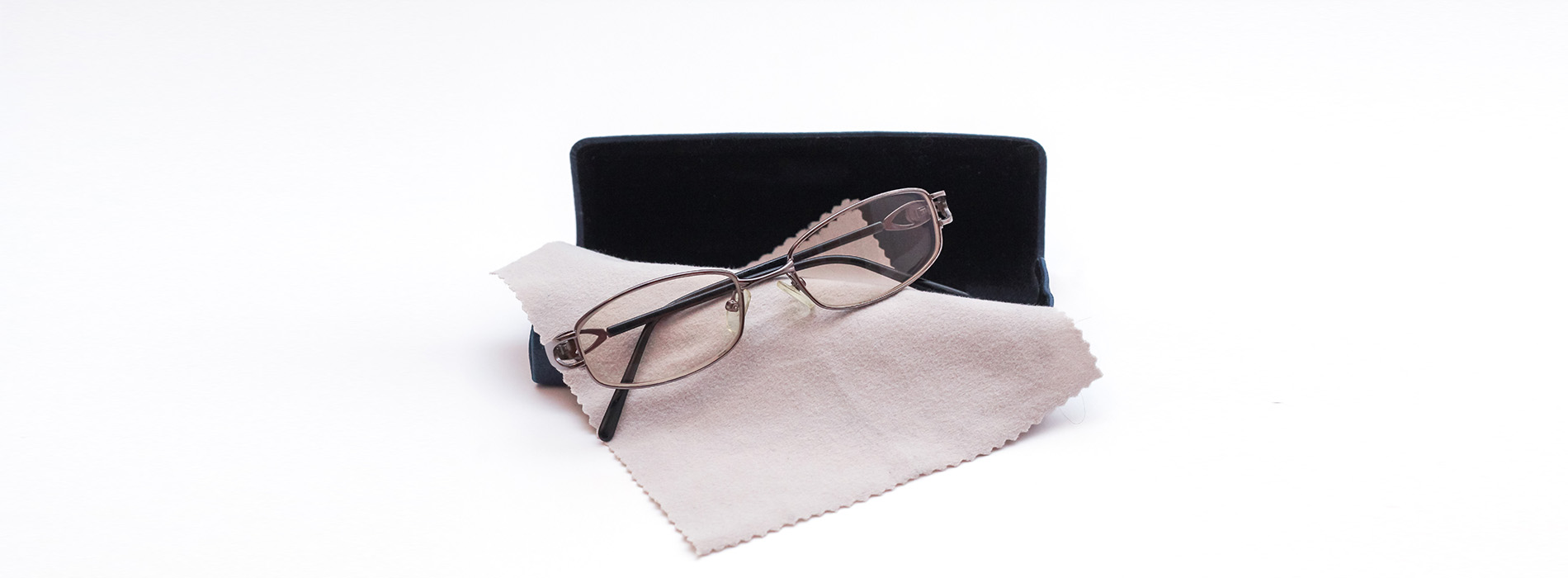 Eyeglasses with a strap on a surface, accompanied by a black case and a piece of paper.