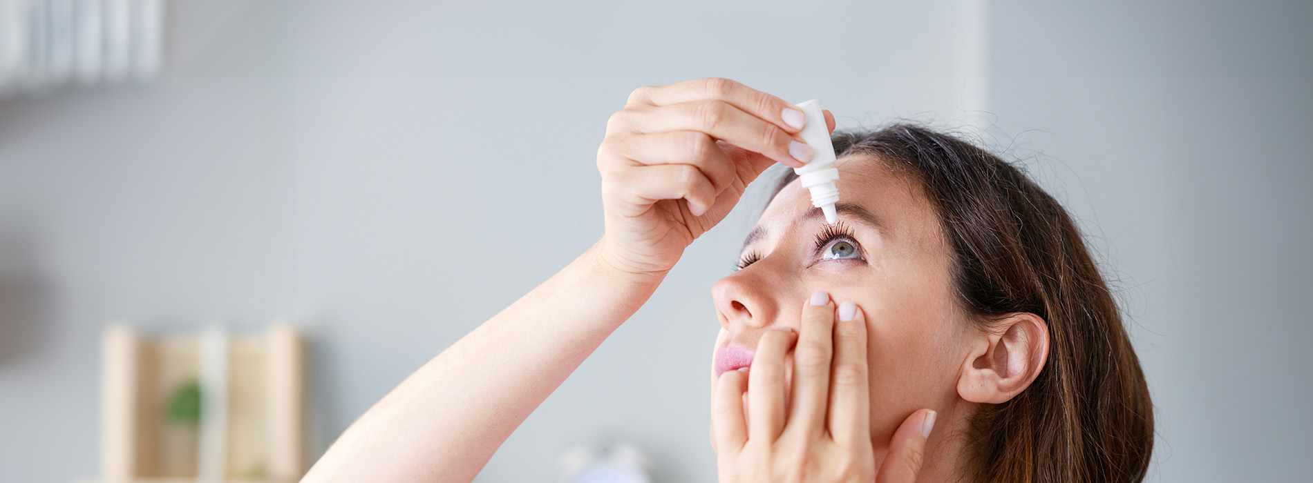 A person applying makeup or skincare to their face in front of a mirror.