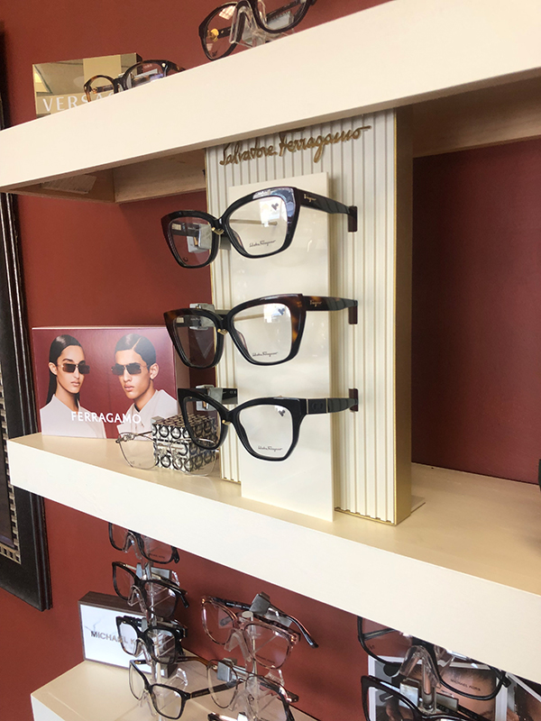 Eyeglass display with multiple pairs of glasses on a shelf.