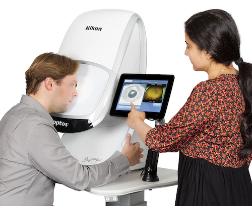 A man and a woman interacting with an optical device, likely related to eye health or vision correction, with the man operating it while the woman observes.