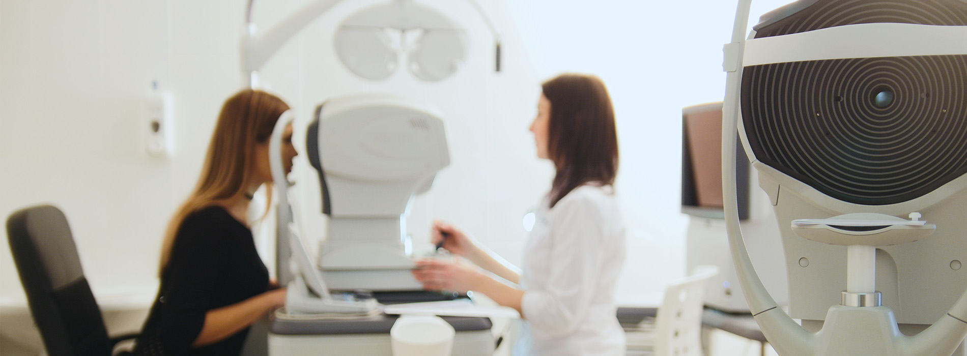 A woman and a man in a professional setting, with medical equipment and a large screen in the background.