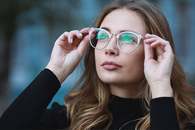 A young woman wearing glasses and a black top, looking intently to the side.