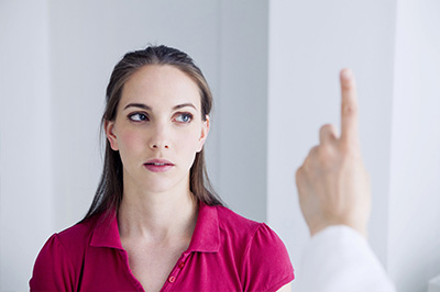 An adult female with a neutral expression, looking off to the side, in a medical setting where she is being shown something on her hand by a healthcare professional.