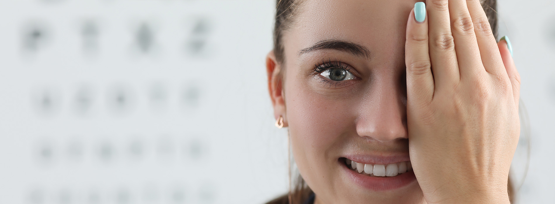 The image shows a woman with her hand on her forehead, appearing to be in a state of surprise or shock. She is indoors, and the background suggests she might be at an eye clinic, given the presence of what appears to be an eye chart.